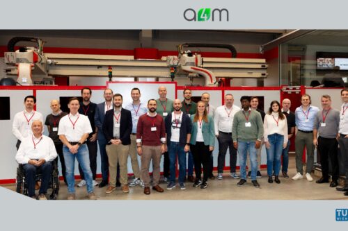 Gruppenfoto der Teilnehmenden des A4M-Konsortialtreffens bei igm Robotersysteme AG in Wiener Neudorf vor einer industriellen Fertigungsanlage.