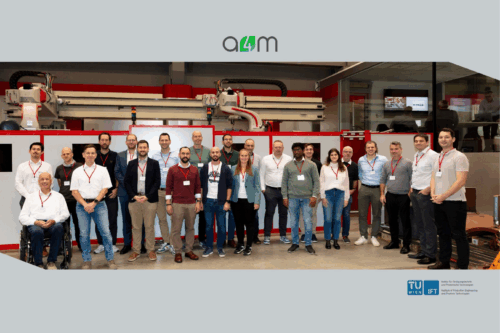 Gruppenfoto der Teilnehmenden des A4M-Konsortialtreffens bei igm Robotersysteme AG in Wiener Neudorf vor einer industriellen Fertigungsanlage.